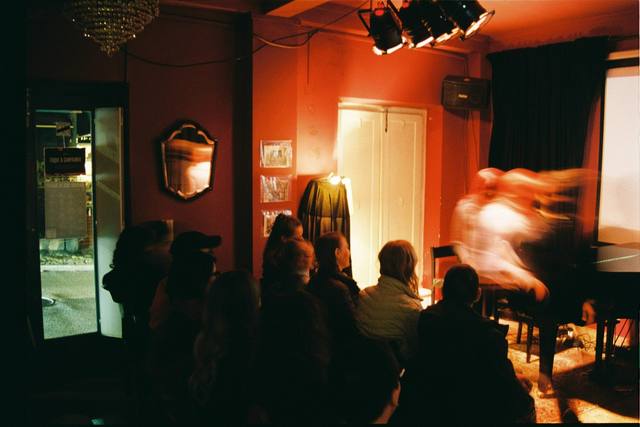 dim red-lit venue, crowd silhouettes