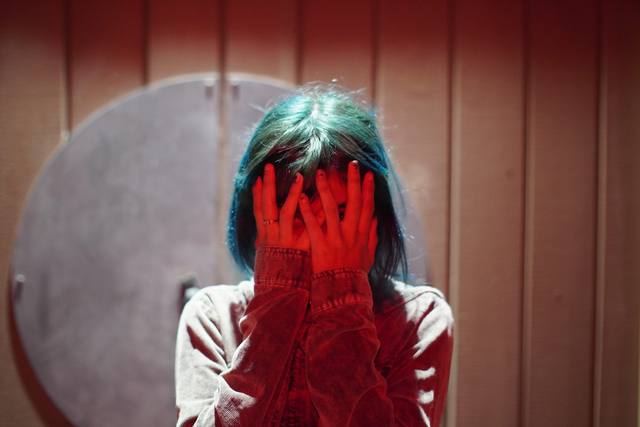 figure in red light, hands over the face